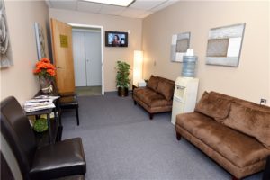 office waiting area couches chairs flowers table door open water cooler wall art