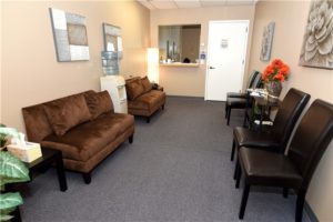 office waiting area couches chairs flowers table door counter wall art
