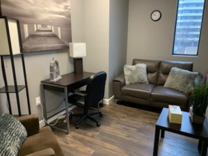 office waiting area hardwood floors couch chairs wall art lamp end table desk