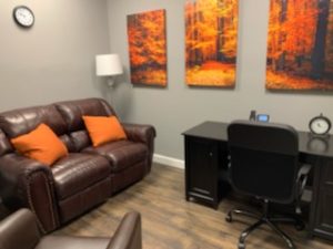 office waiting area couch chairs desk clock wall art