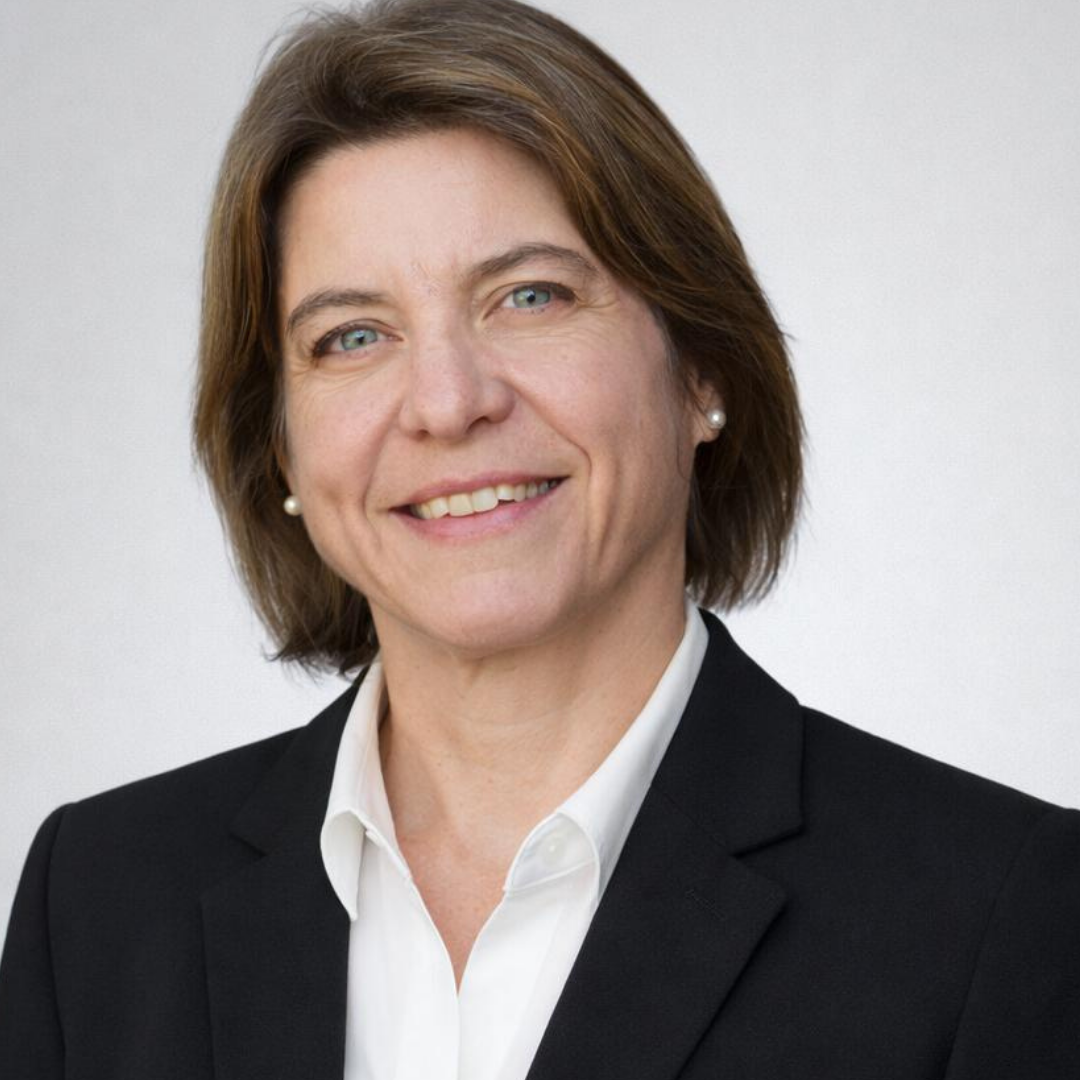 Smiling woman with short brown hair wearing a black blazer and white shirt