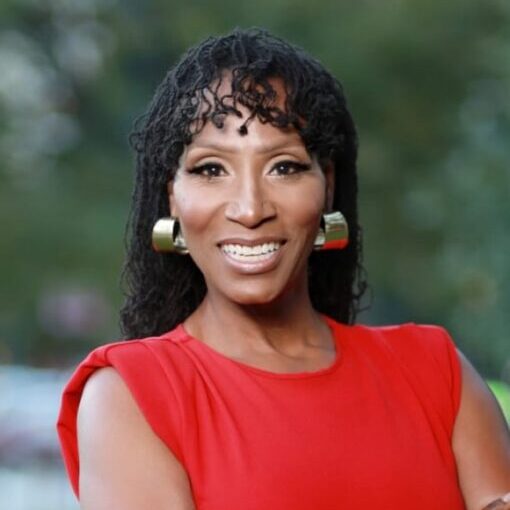 Smiling woman in a red dress with gold earrings posing outdoors