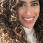 Woman with curly highlighted hair smiling warmly.